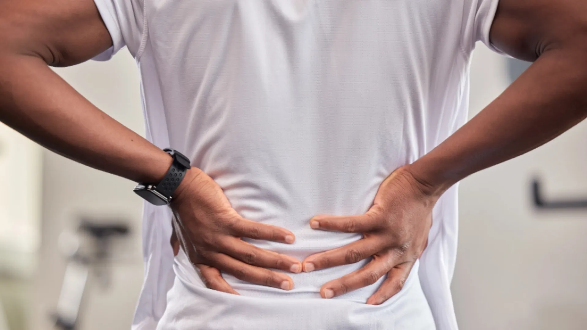 A person is holding their back in discomfort and pain.