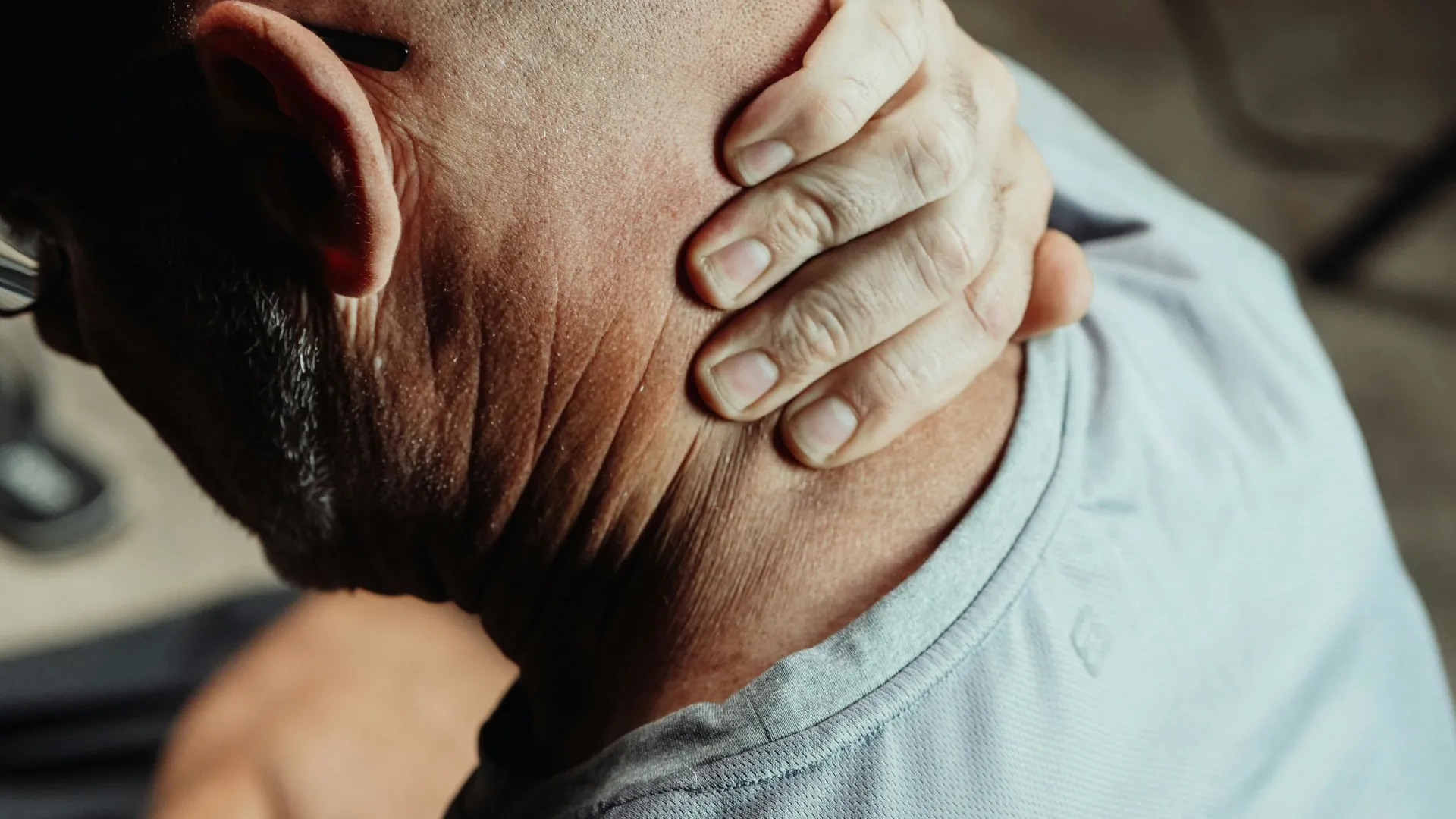 An older man is feeling his neck, he has neck pain.