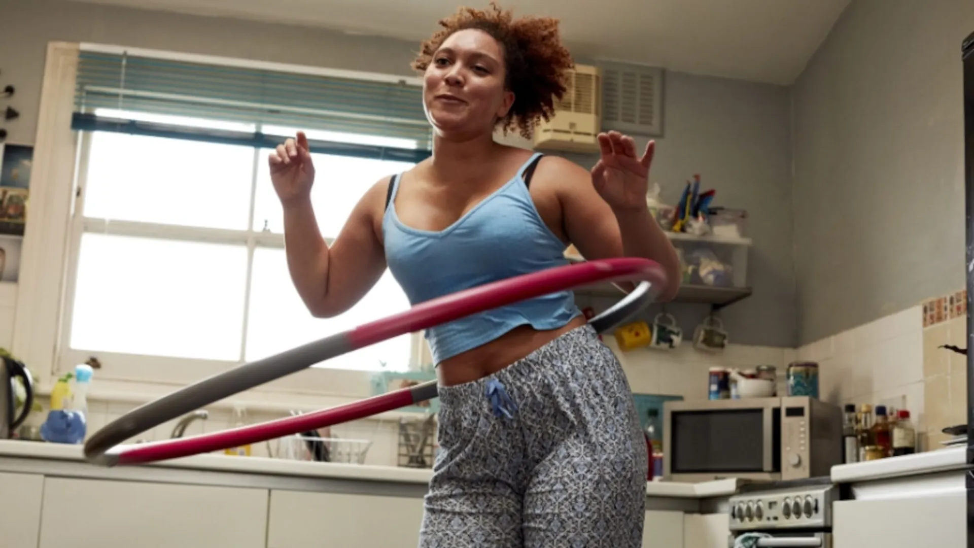 A woman is keeping her hips active with the hula hoop.